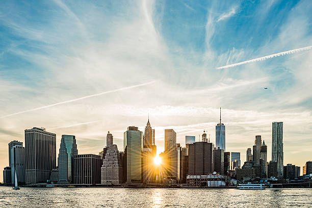 sunburst tra gli edifici dello skyline di manhattan a new york - queens foto e immagini stock