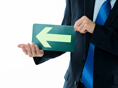 Businessman holding a green arrow forward against white background.