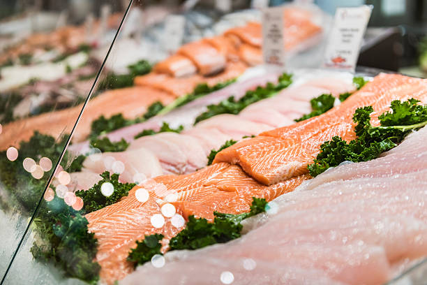 Seafood stand with cuts and filets of salmon and tuna Seafood stand with cuts and filets of salmon and tuna on ice behind glass commercial tuna fishing stock pictures, royalty-free photos & images