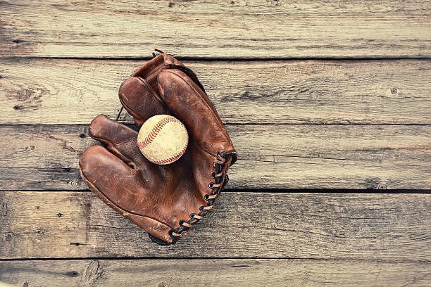 istock Old leather baseball mitt and ball on grunge wood background 543666154
