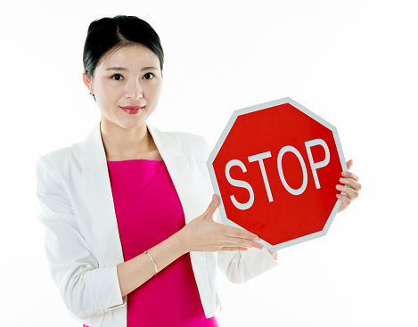 Young woman holding STOP sign against white background.