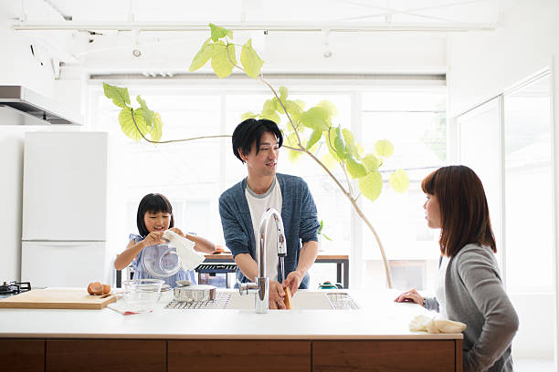 キッチンで一緒に皿を洗う若い家族 - 朝 ストックフォトと画像