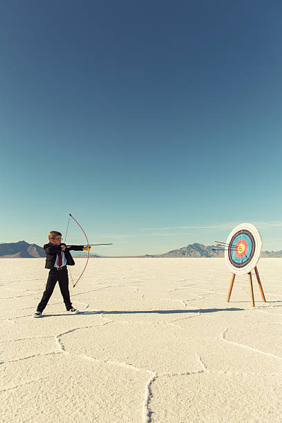 istock Young Boy Businessman Shoots Arrows at Target 543674228