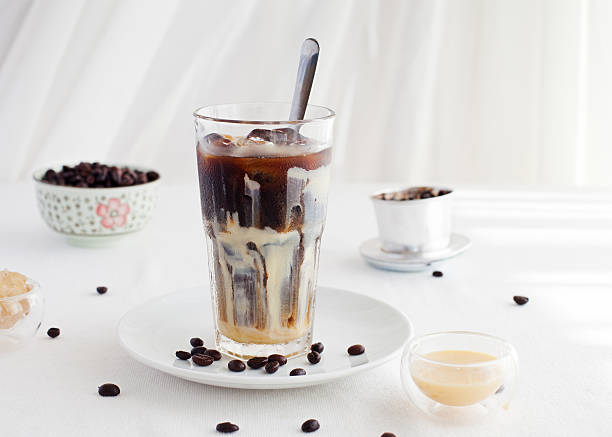 Ice coffee with condensed milk, traditional Vietnamese, Thai drink Ice coffee with condensed milk, traditional Vietnamese, Thai coffee with coffee beans on a white plate background vietnamese culture stock pictures, royalty-free photos & images