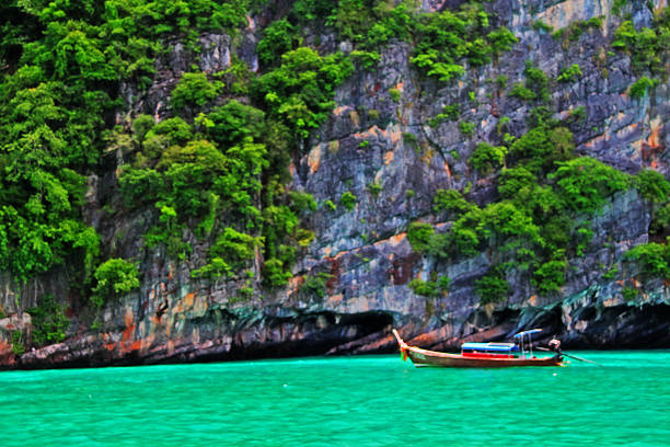 Krabi, Thailand - May 28, 2013 - Tourist sightseeing boats with rock mountain at Maya bay in Andaman sea.
