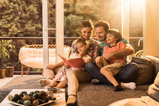 Happy parents reading a book with their small kids.