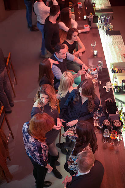 Large group of friends enjoying drinks in bar, having fun