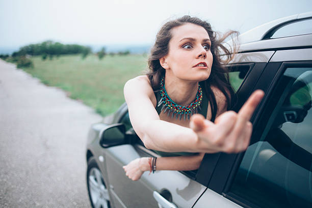 istock Young woman making rude gesture on road 543682560