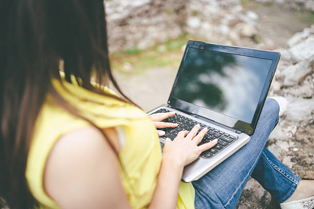 istock young woman using laptop outdoors 543684122