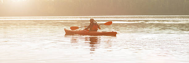 istock Man paddles canoe in river at sunrise 543687012