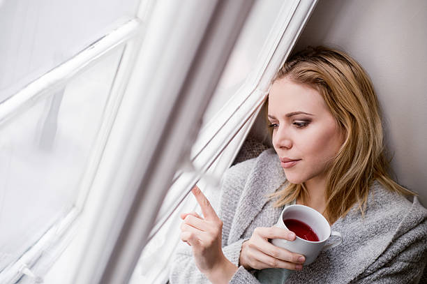istock Woman on window sill holding a cup of tea 543687072