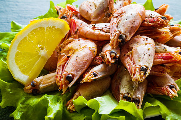 istock Big boiled shrimps and lemon on green lettuce. 543687140