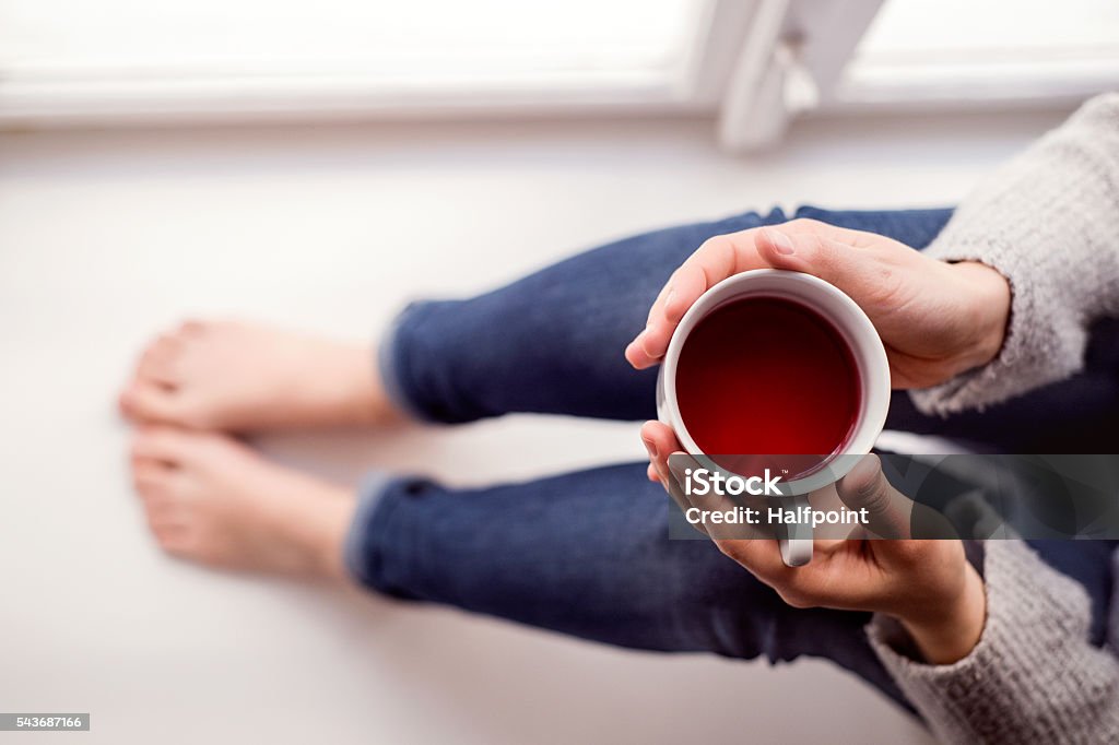 Mujer en el alféizar sosteniendo una taza de té - Foto de stock de Té - Bebida caliente libre de derechos
