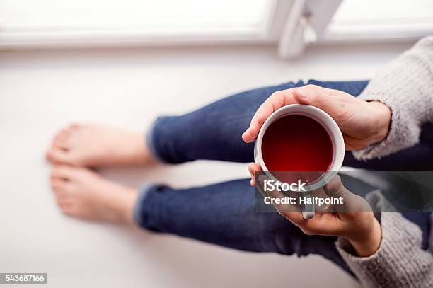 Mujer En El Alféizar Sosteniendo Una Taza De Té Foto de stock y más banco de imágenes de Té - Bebida caliente - Té - Bebida caliente, Gente tranquila, Relajación