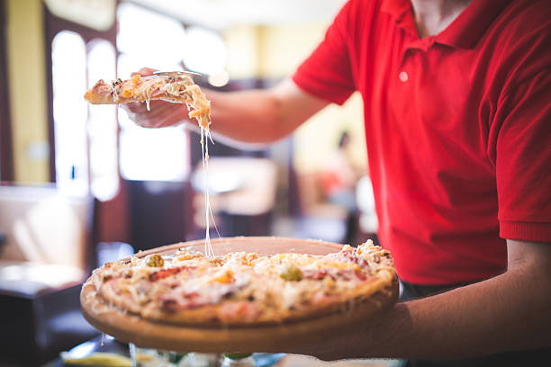 Young cheerful hispanic woman pizzeria owner inviting to taste delicious pizza in cozy atmosphere