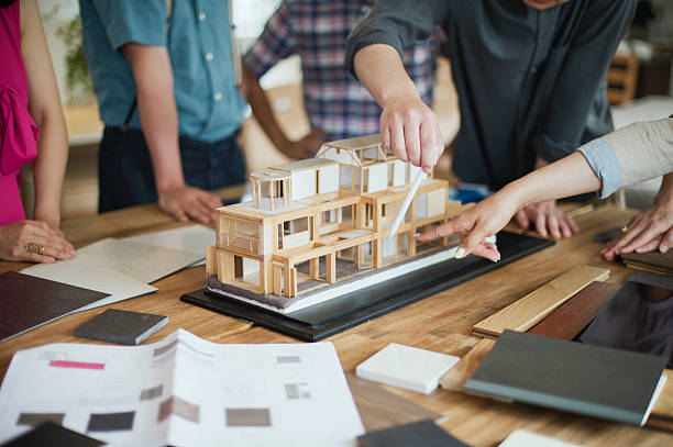Team of interior designers discussing in the studio Workers meeting in architectural design studio with digital tablet and materials and architectural models. architectural model photos stock pictures, royalty-free photos & images