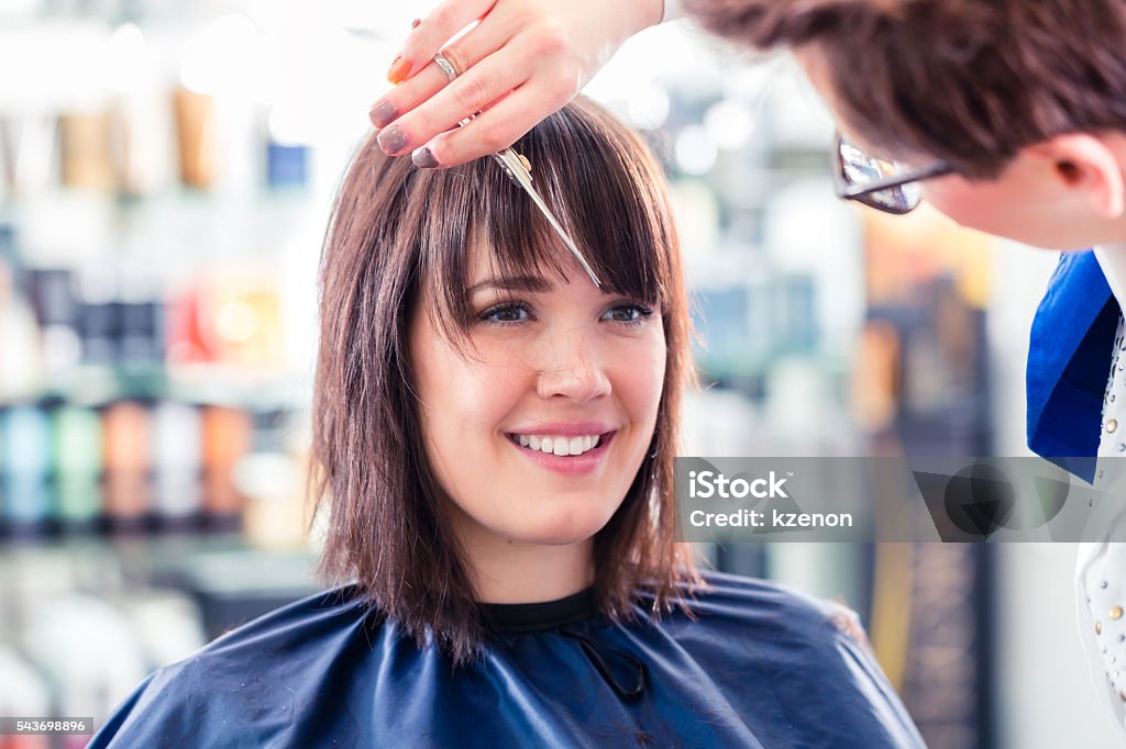 Hairdresser cutting woman hair in shop Female coiffeur cutting women hair in hairdresser shop Bangs - Hair Stock Photo