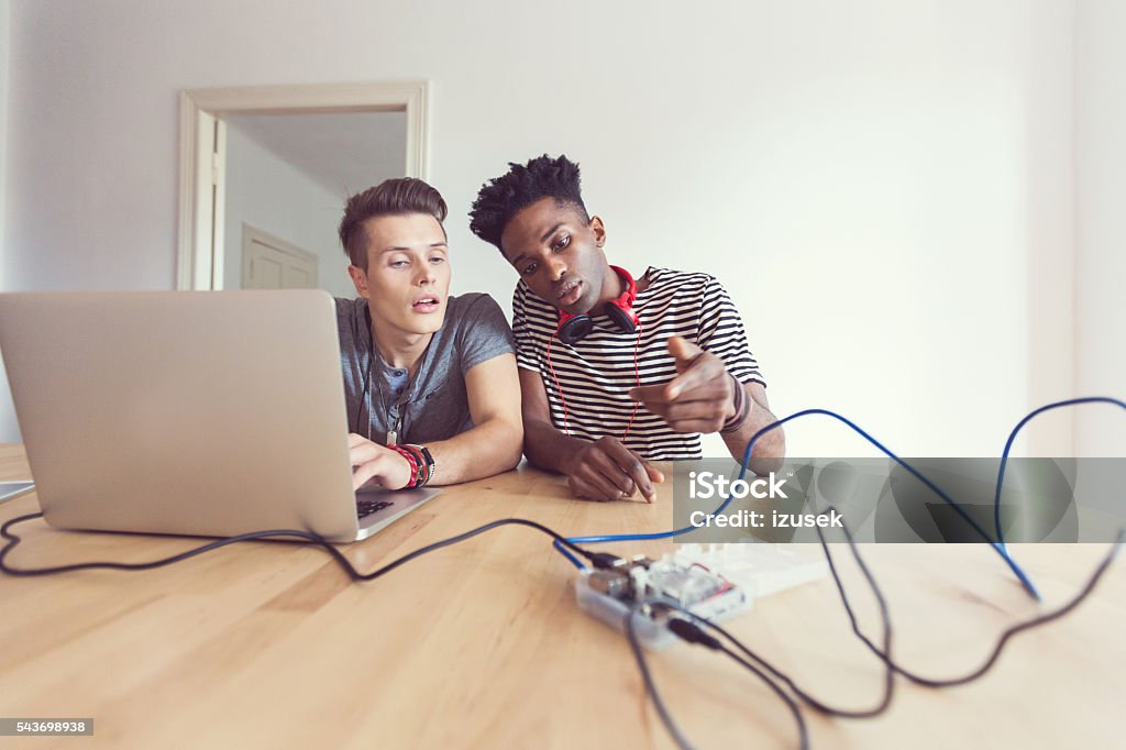 Friends programming mico computer Two male students stiiting at the table and programming mico computer. 20-29 Years Stock Photo Friends programming mico computer Two male students stiiting at the table and programming mico computer. 20-29 Years Stock Photo