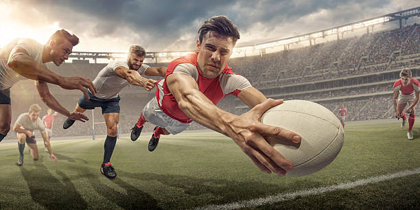 A generic seated rugby stadium showing a rugby ball on a green grass pitch in the day time under a blue cloudy sky - 3D render