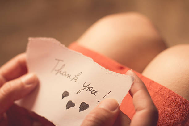 Woman holding a thank you note in her hand Top view of a woman with pink dress holding a thank you note in her hand with shallow depth of field woman legs open stock pictures, royalty-free photos & images