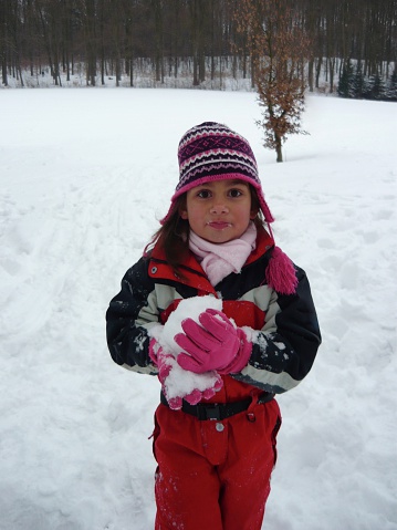 Little girl having fun eating the fluffy white snow
