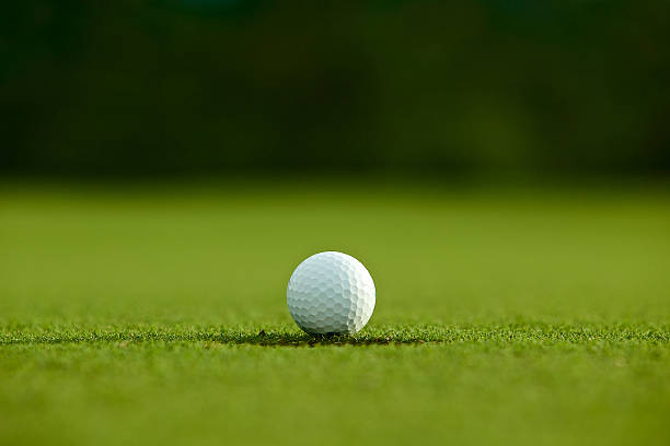 istock selective focus. white golf ball near hole on green grass 543818298
