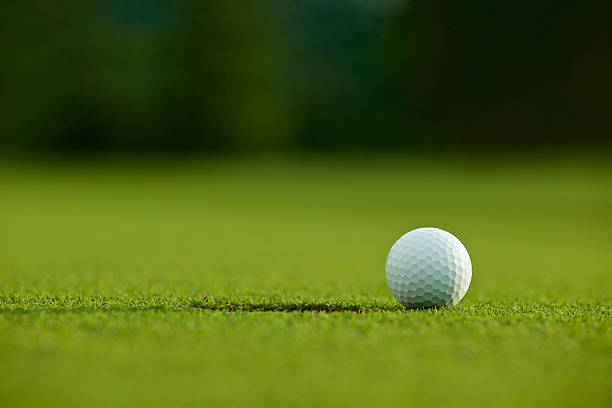 istock selective focus. white golf ball near hole on green grass 543819046