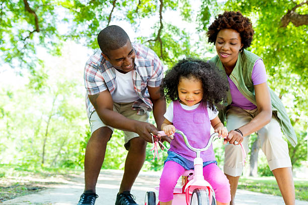 istock Mom and dad help toddler ride tricyle 543819420