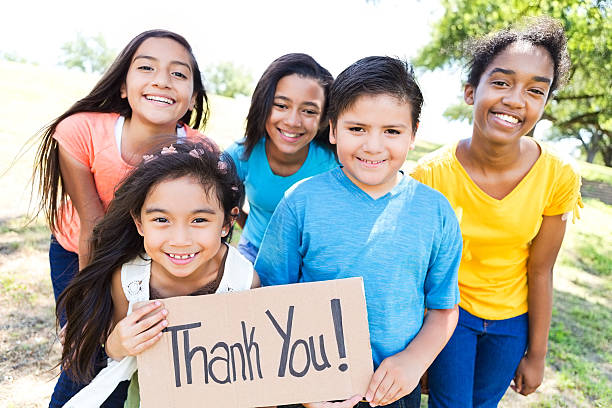 Young diverse friends in local park hold 'Thank You!' sign Cute diverse elementary, preteen and teen friends hold 'Thank You!' sign in their neighborhood park.  It is a sunny summer day. thank you phrase stock pictures, royalty-free photos & images