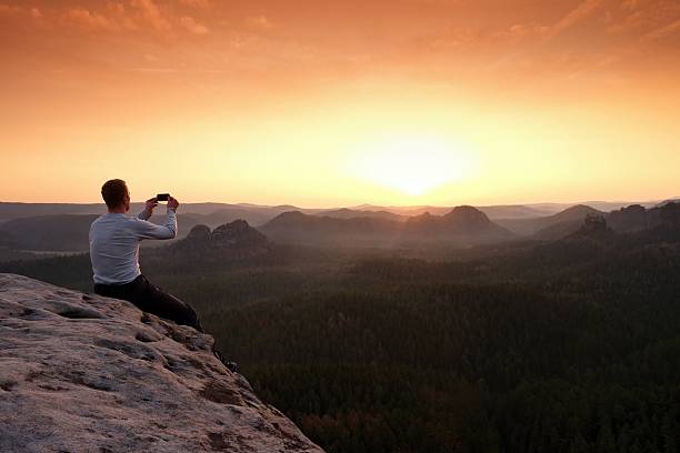 istock Tall tourist at dangerous cliff edge is taking selfie 543823394