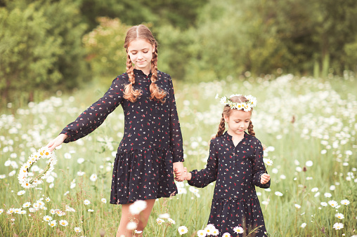 two happy girls are walking embraced outside in nature