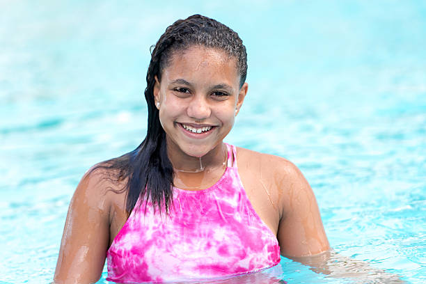 Twelve years old little girl looking at the camera smiling in the swimming pool