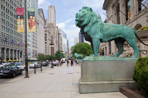 Chicago, Illinois, USA - June 22, 2016: close-up of a lion in front of Art Institute. Some people are visible on the sidewalk.