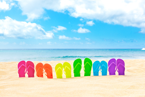 LGBT community vacation destination, a row of rainbow color flip flop on a white sand beach in tropical paradise. Spring break, vacation tailored for the LGBT community.