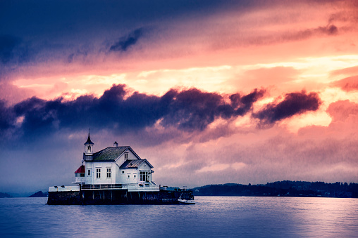Old Church Perched on Stone in The Middle of Norwegian Fjord at sunset storm.