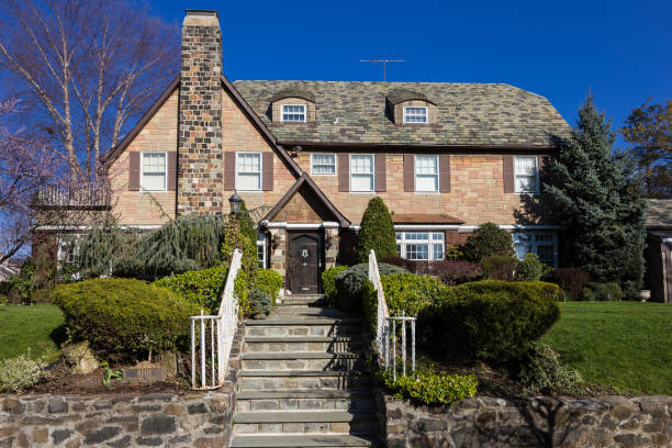 New York, NY, USA - April 12, 2016: Luxury Red Brick House with Slate Roof and Steps in Bay Ridge neighbourhood of Brooklyn, New York, USA. Trees, bushes, green grass and clear blue sky are in the image. The image lit by the evening sun. Canon EOS 6D (full frame) and EF 24-105mm f/4L IS lens.