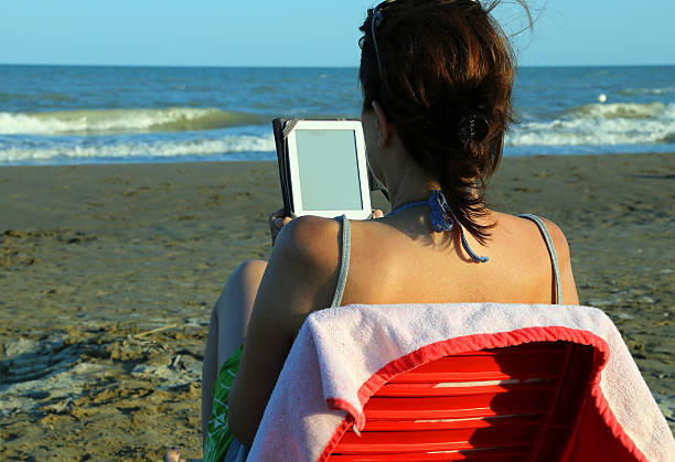 istock woman reads the ebook on the beach 543838132