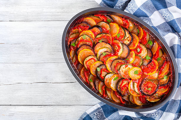 traditional French vegetable casserole ratatouille, top view traditional French casserole -  ratatouille: stewed zucchini, red bell pepper, parsley, yellow squash, eggplant, tomato sauce and garlic in baking dish, close-up ratatouille stock pictures, royalty-free photos & images