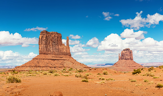 Scenic view to the famous West Mitten Butte and Merrick Butte under beautiful summer sky. Monument Valley, Arizona, USA.