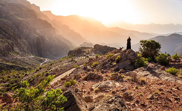 Lone woman in abaya in Al Hajar Mountains of Oman at sunset
