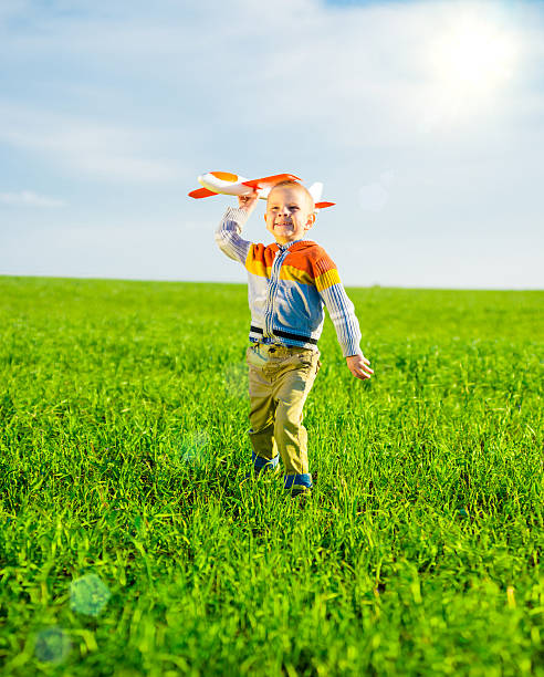 istock Happy boy playing with toy airplane against blue summer sky 543985158