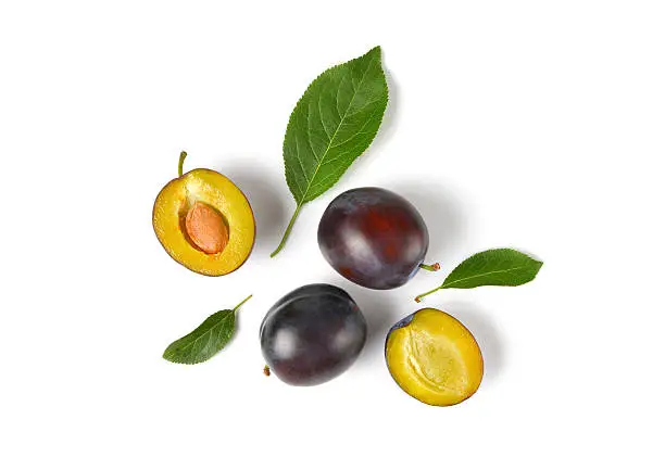ripe plums with leaves on white background