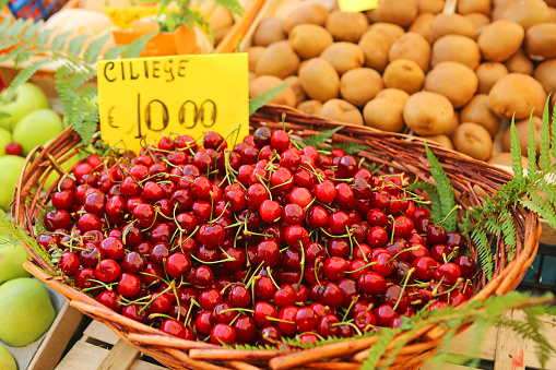 A basket of fresh red cherries and other fruit for sale at Campo de Fiori market in Rome.