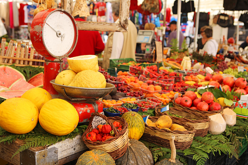 Variety of fruit for sale at Campo de Fiori market in Rome, Italy. Fruit stall at this popular market is decorated with an old-fashioned weight scale. Fruits for sale include ponderosa lemon, watermelon, strawberry, banana, cherry...