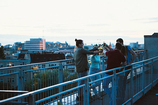istock small group, young adults on rooftop, talking, toasting beer, skyline 543992528