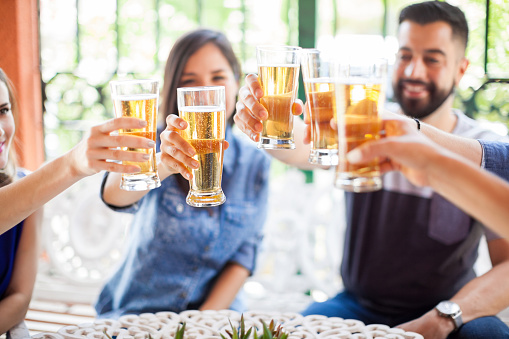 Closeup of a group of good friends spending time together and making a toast with some cold beers outdoors