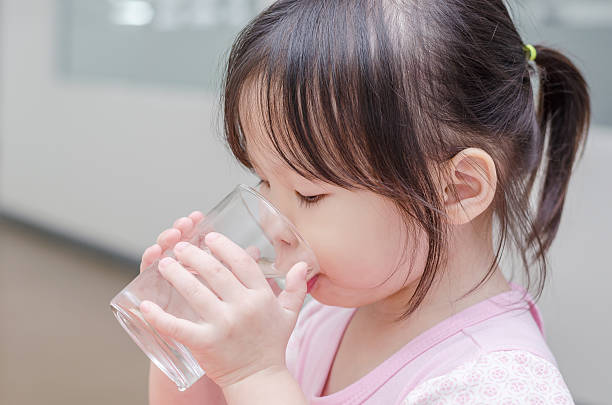 Little girl drinking water from glass stock photo