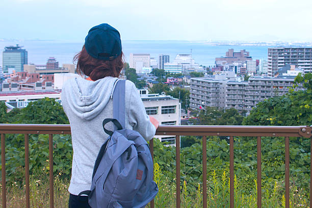 Young woman looking at her town A young woman is standing on slightly higher palce and looking at her town. She is watching architectures and a lake. May be, she is coming back to her home after school. suwa lake photos stock pictures, royalty-free photos & images