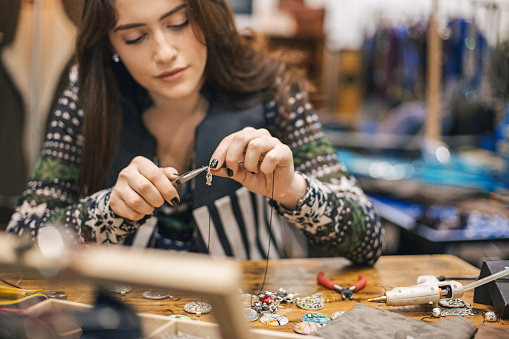 Attractive young woman creating handmade jewelry in her studio