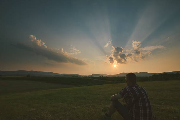 istock Man sitting on the field in front of setting Sun 544099826
